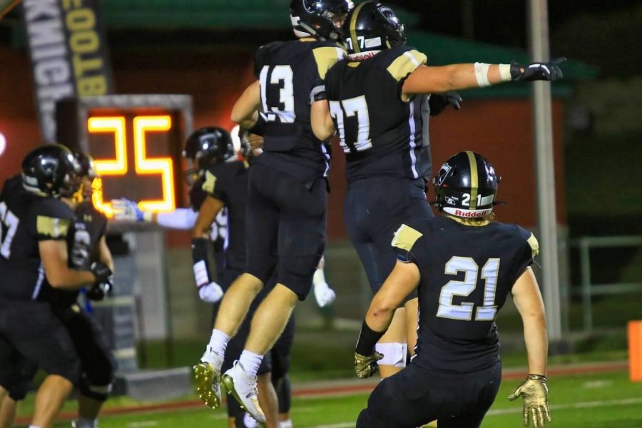 Isaac Gifford (13) celebrates with teammates Xavier Trevino (77) and Nick Halleen (21) after a touchdown.