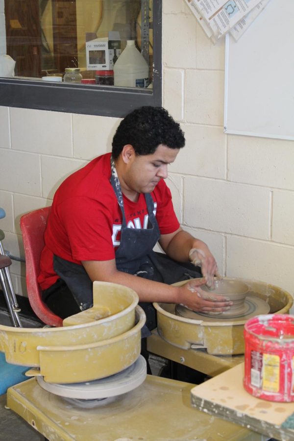 Julian Silverio (12) gently shapes the wet clay before him into a bowl.