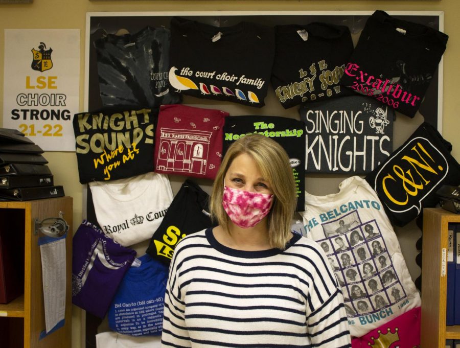 Southeast High School Choir Director Melissa Noonan poses in front of choir shirts from the past. 